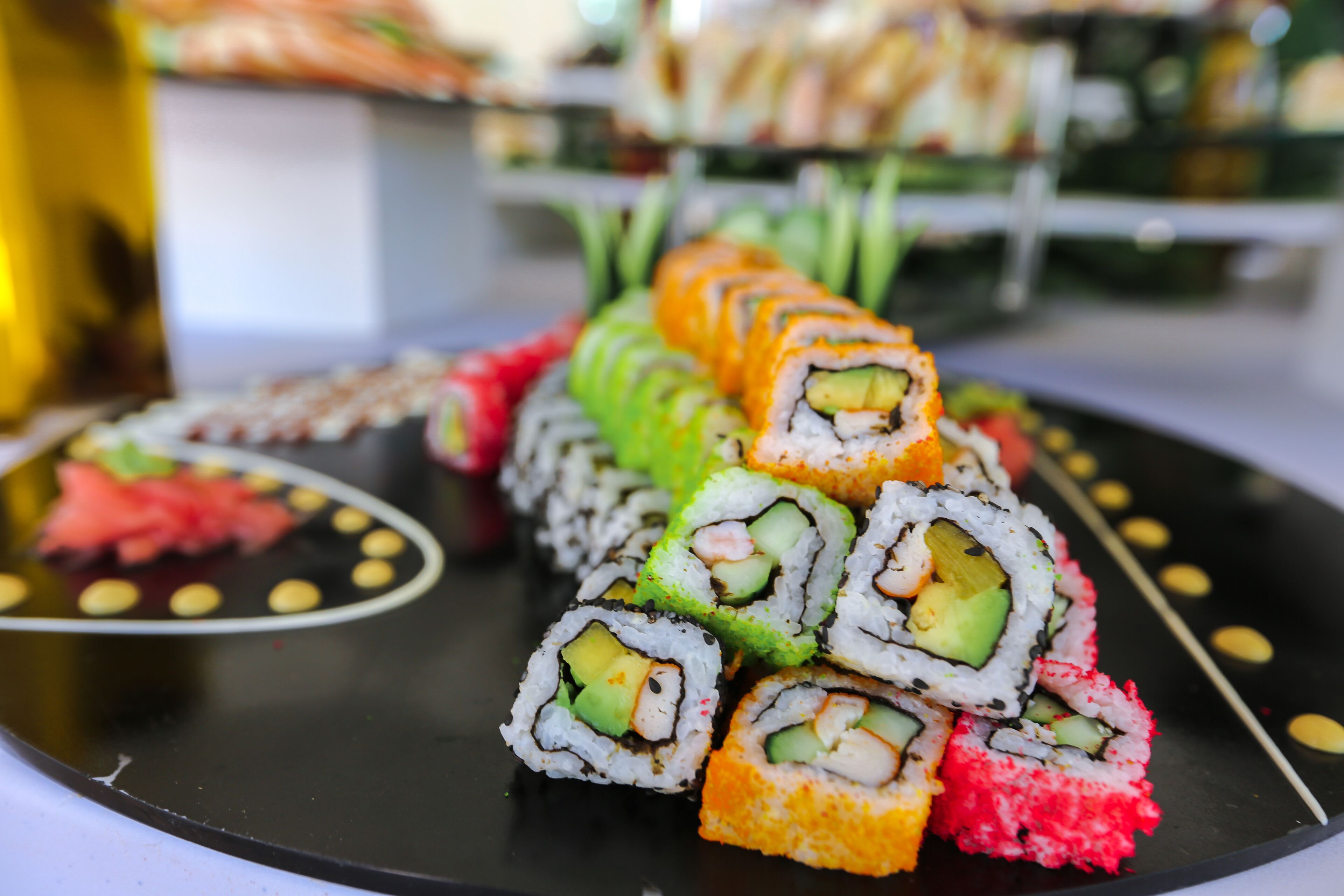 Diverse porzioni di sushi disposte su un piatto nero con bordo decorativo.