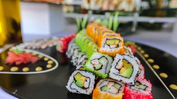 Diverse porzioni di sushi disposte su un piatto nero con bordo decorativo.