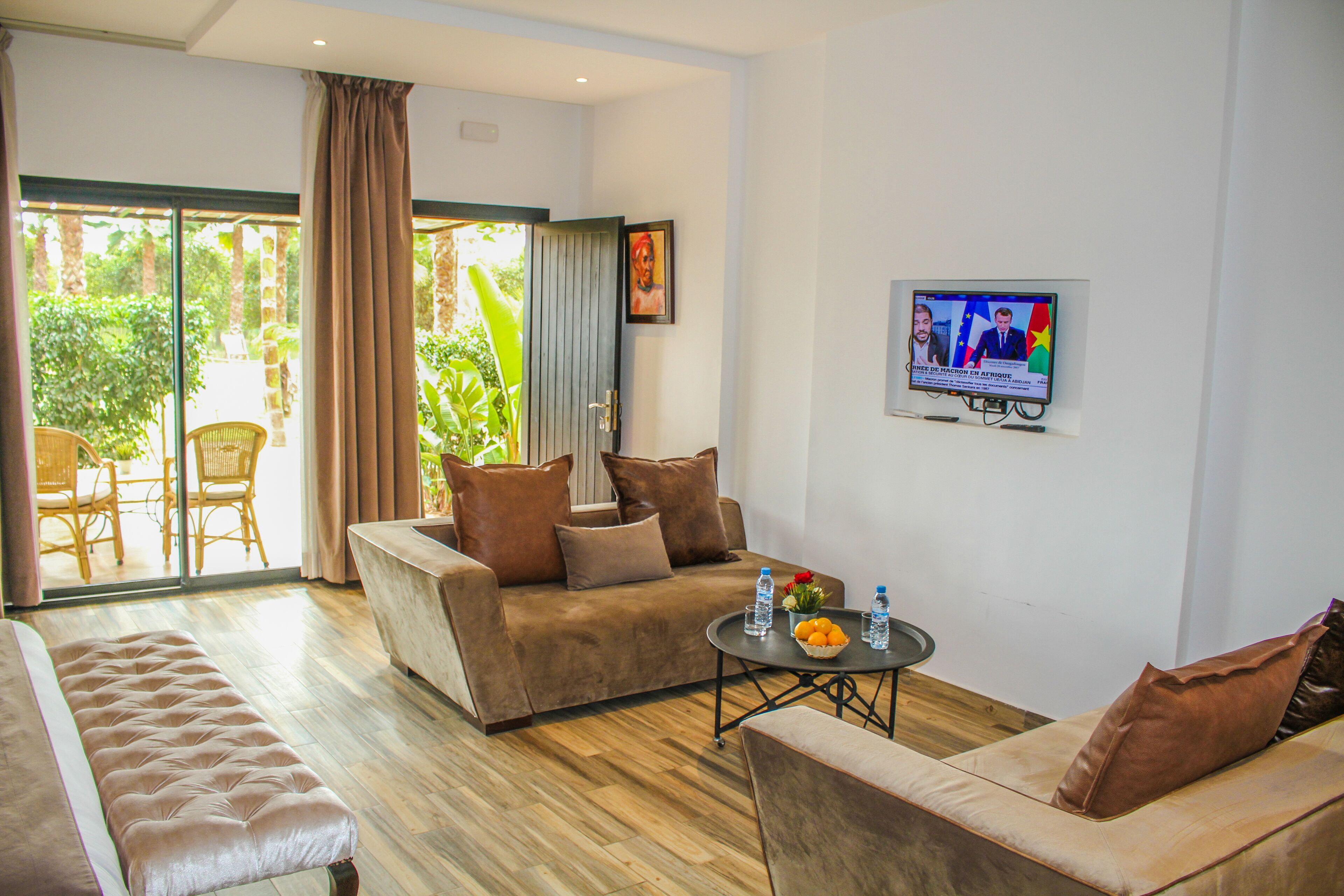 Uma sala de estar moderna com sofá, poltrona e mesa de centro com uma fruteira e garrafas de água.