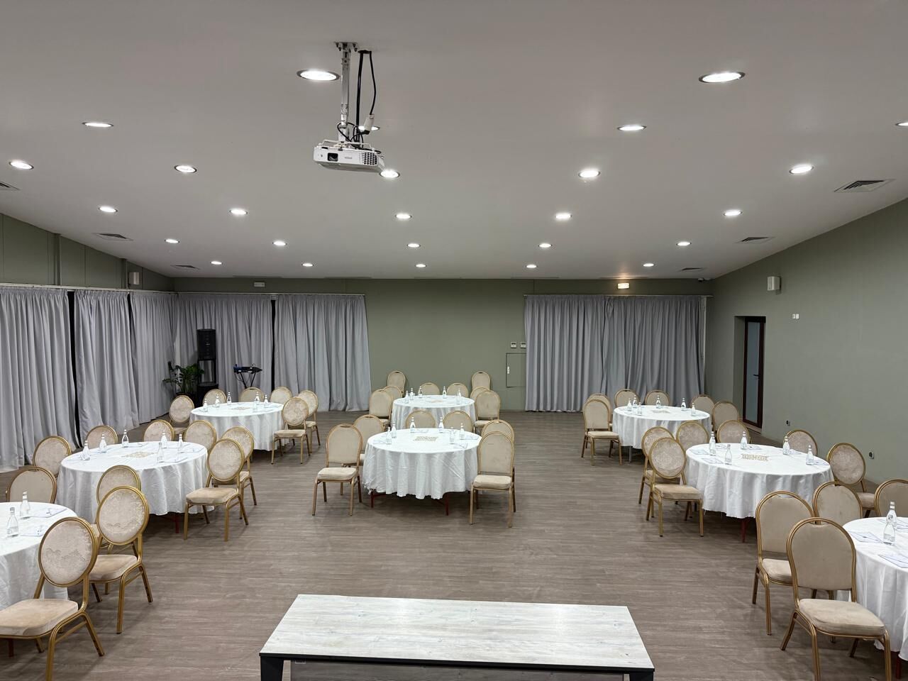 A conference room with round tables, chairs, and a projector.