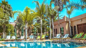 A pool area with lounge chairs and palm trees.