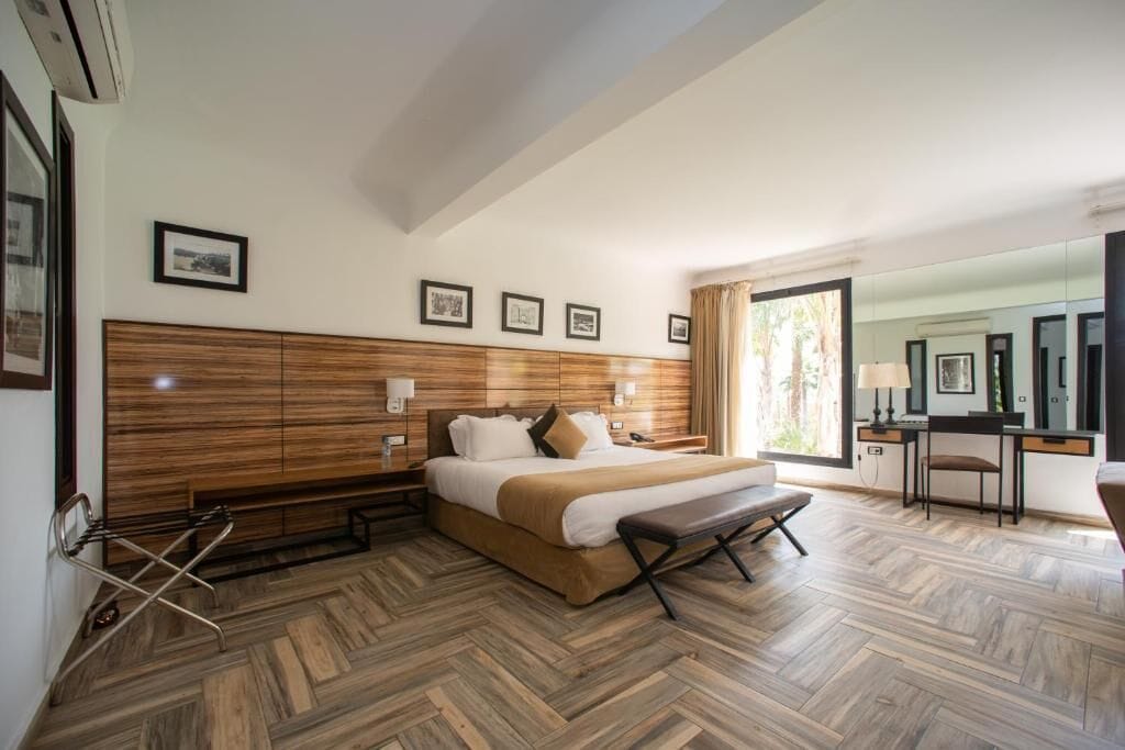 A hotel room with a large bed, wooden headboard, bedside tables, a desk, and a chair.