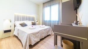A hotel room with a bed, a TV mounted on the wall, and a window with curtains.