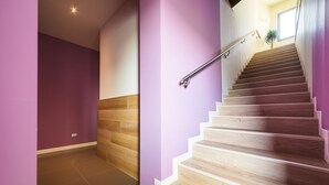 A staircase with wooden steps and a metal handrail, leading to an upper floor.
