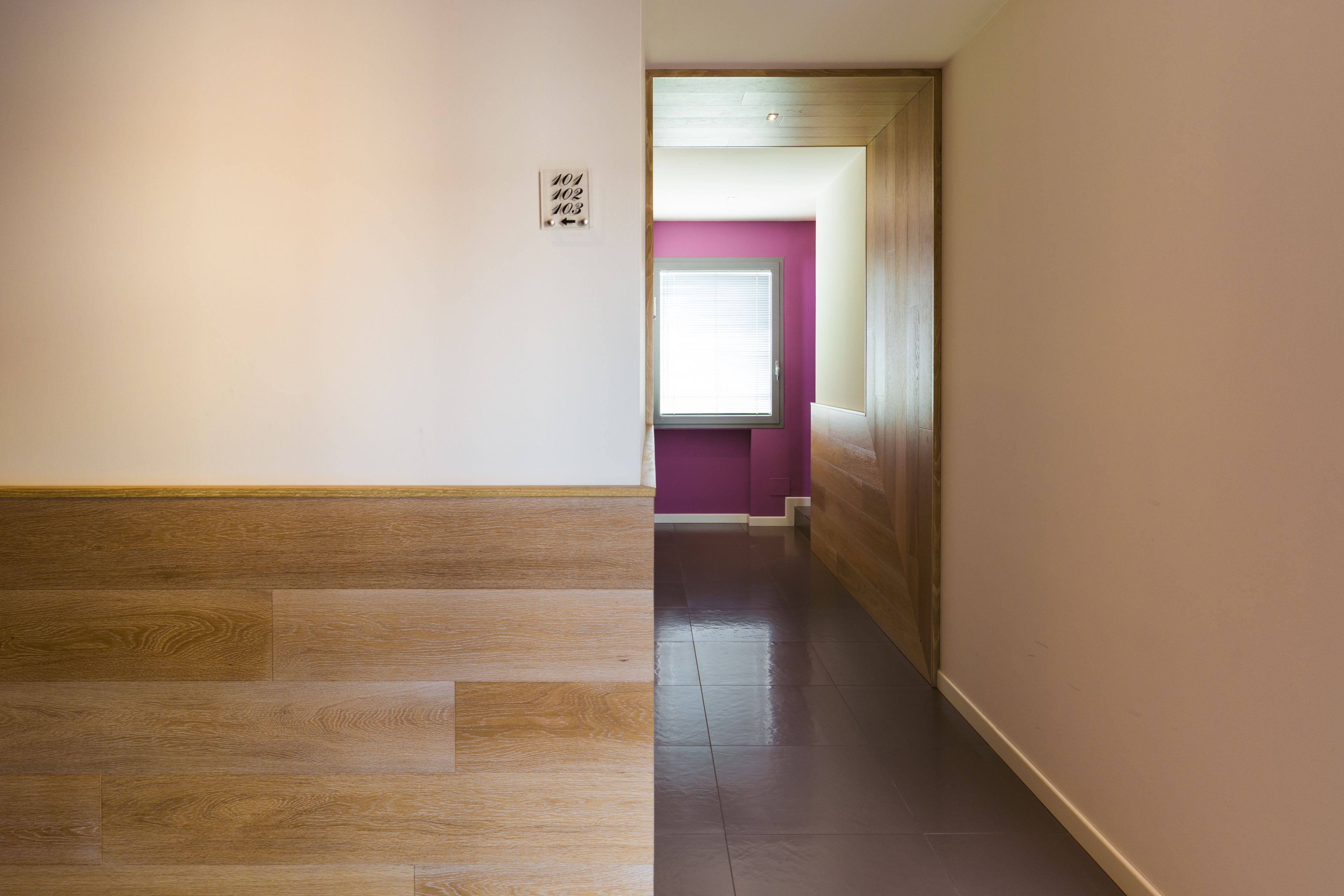 Ein Korridor mit Holzboden und einer violetten Wand.