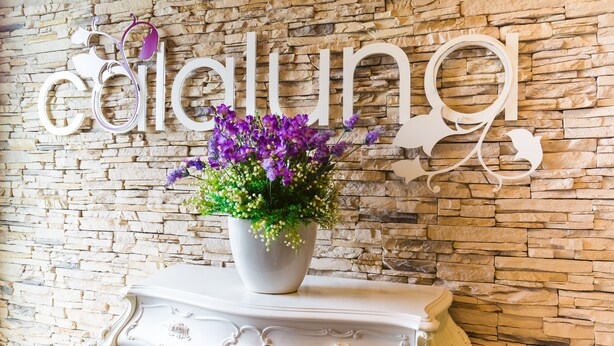 A stone wall with the word "célalung" and a floral arrangement on a white console table.