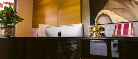 A reception desk with a laptop, a golden bell, and a framed picture.