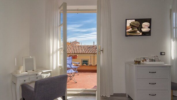 A room with a white desk, a chair, a white dresser, and a framed picture on the wall. - 7 Rooms (Pisa)