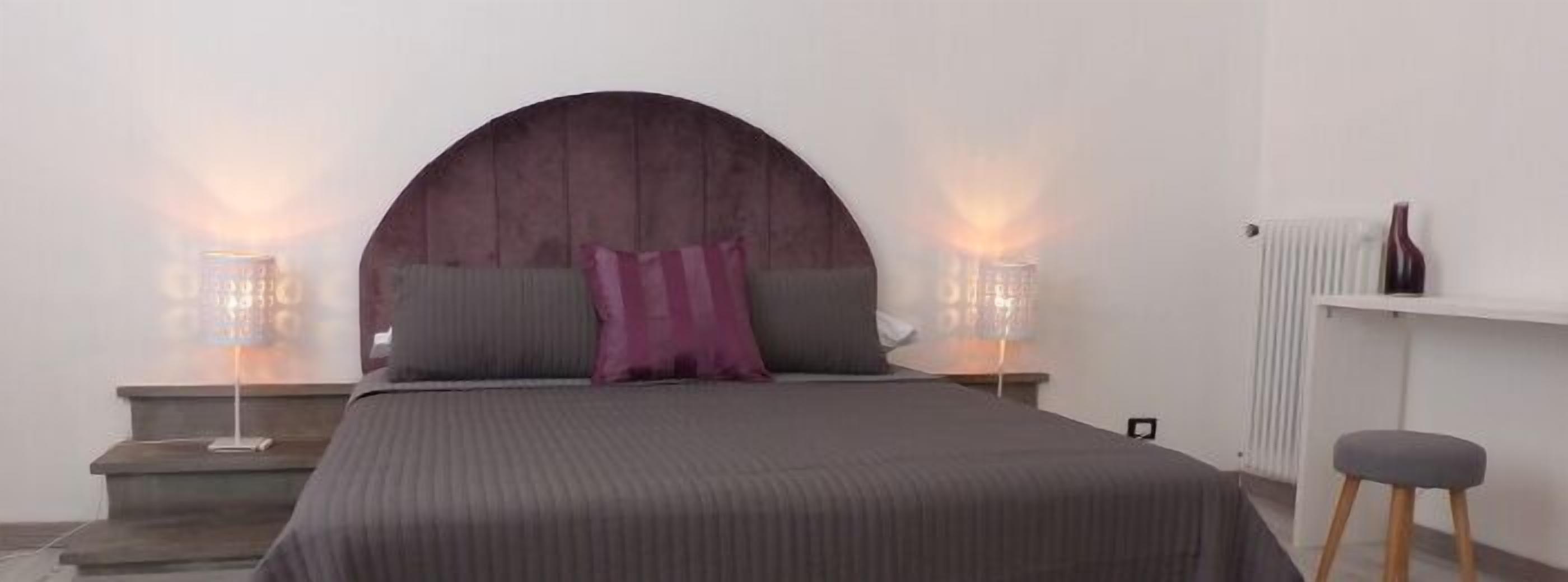 Ein Schlafzimmer mit einem Bett, zwei Nachttischen, einem Heizkörper und einem Hocker.