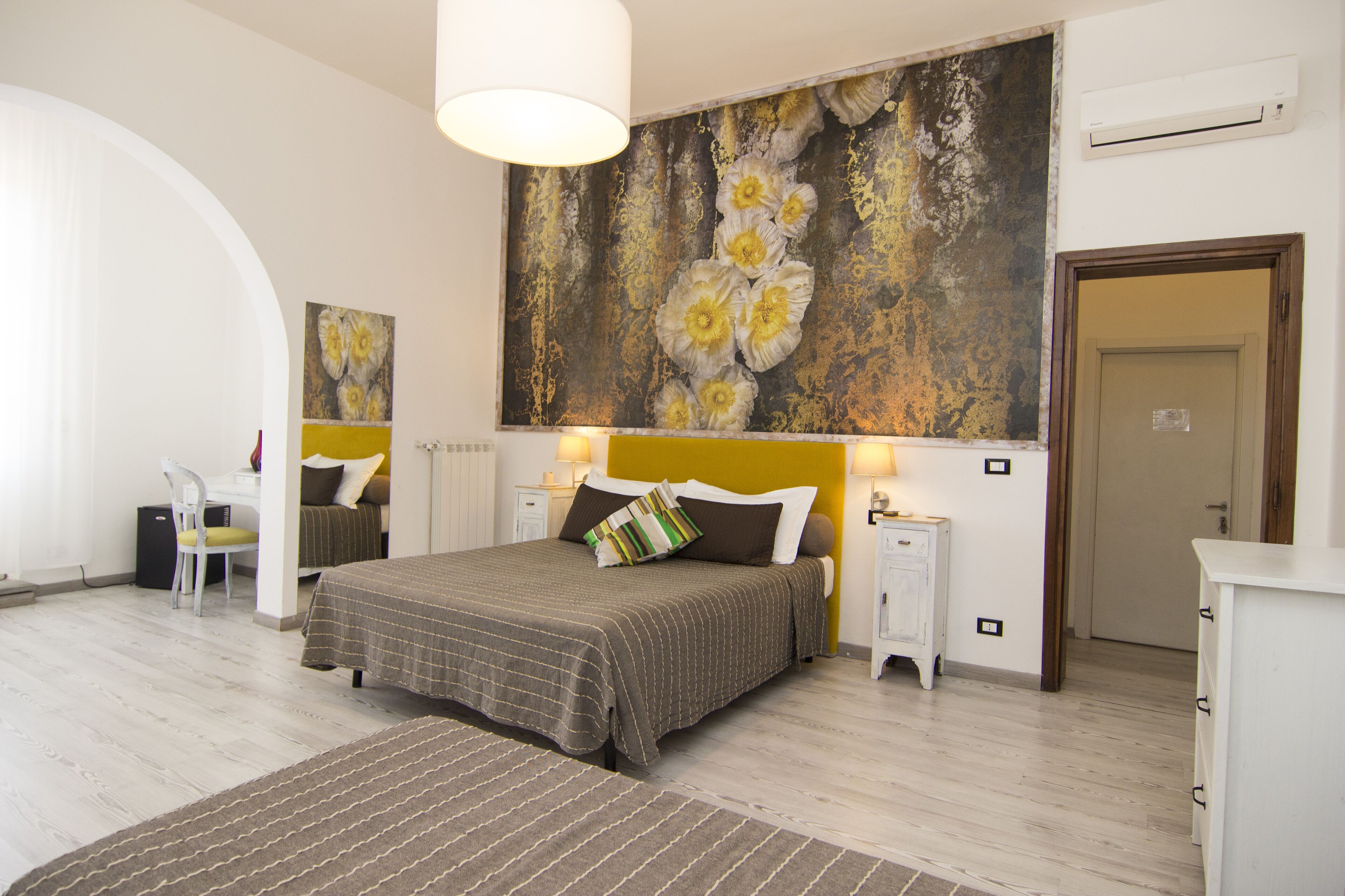 A bedroom with a large bed, bedside tables, a chair, and a painting on the wall.