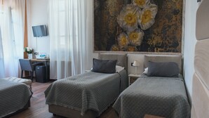 A hotel room with two single beds, a desk with a chair, a TV mounted on the wall, and a large floral painting above the bed. - 7 Rooms (Pisa)