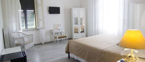 Una habitación de hotel con cama, escritorio, silla, armario y candelabro.