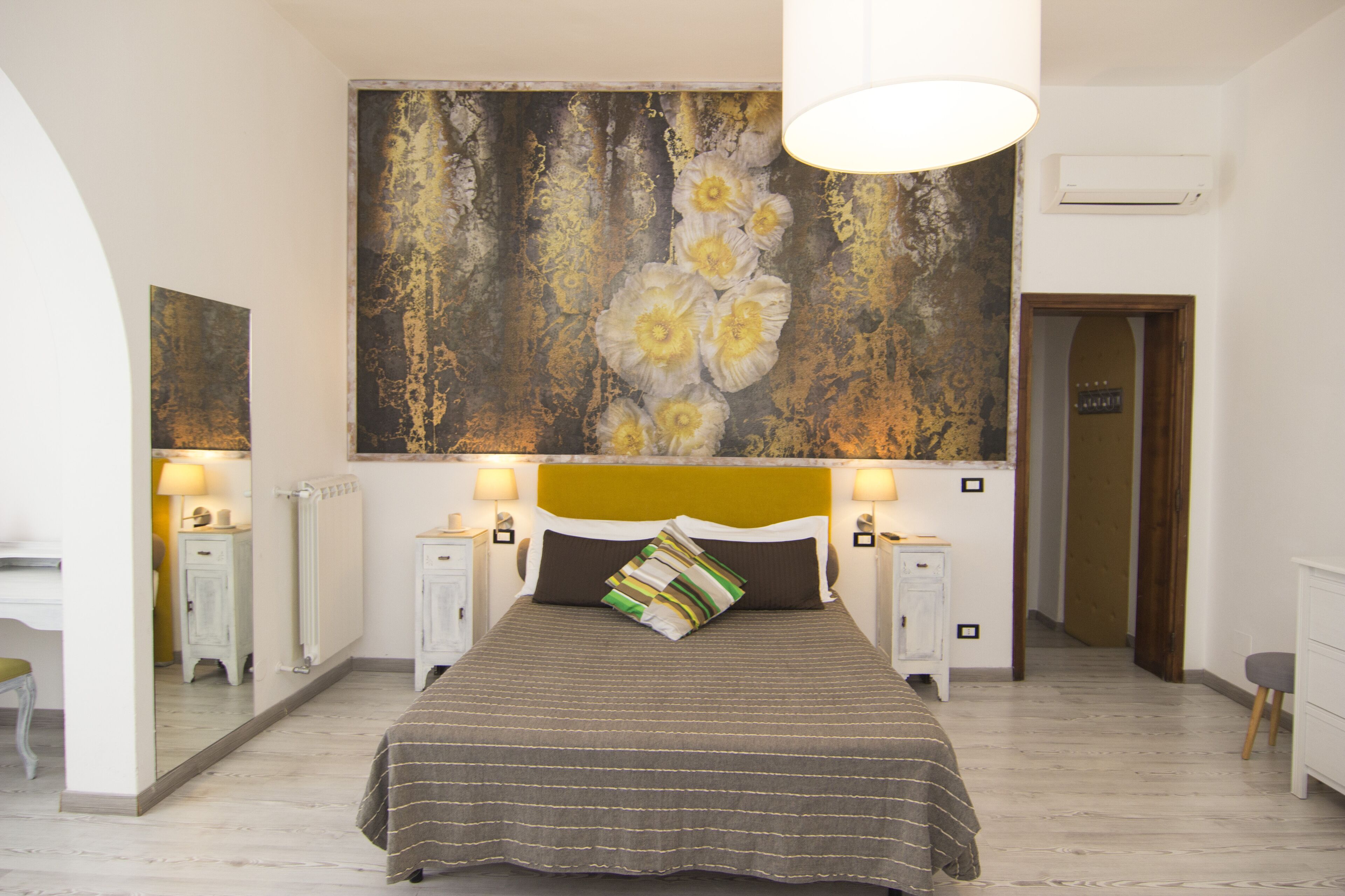 Una camera da letto con un letto grande, comodini, uno specchio e un quadro appeso al muro.