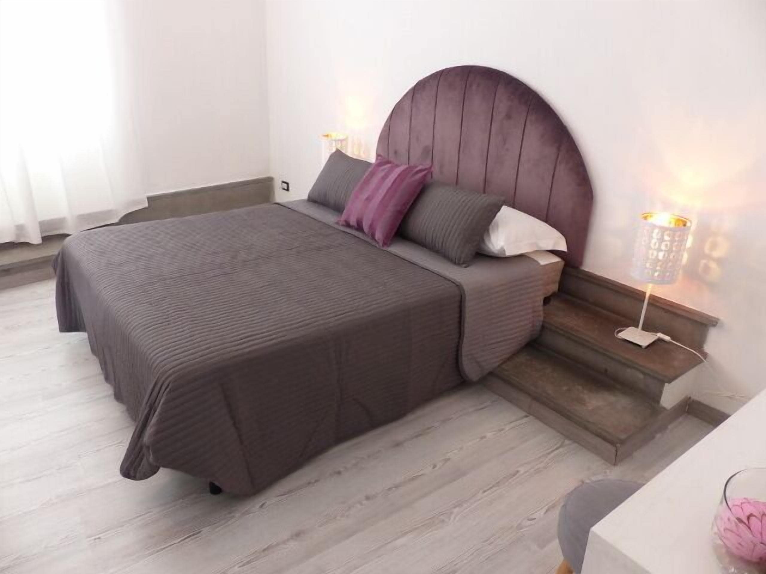 A bedroom with a bed, a nightstand, a lamp, and a chair.