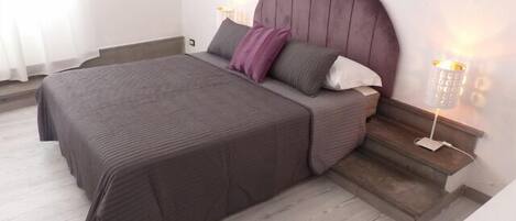 A bedroom with a bed, a nightstand, a lamp, and a chair.