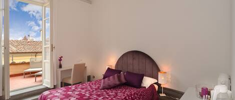 Un dormitorio con cama, escritorio, silla y vistas al exterior.