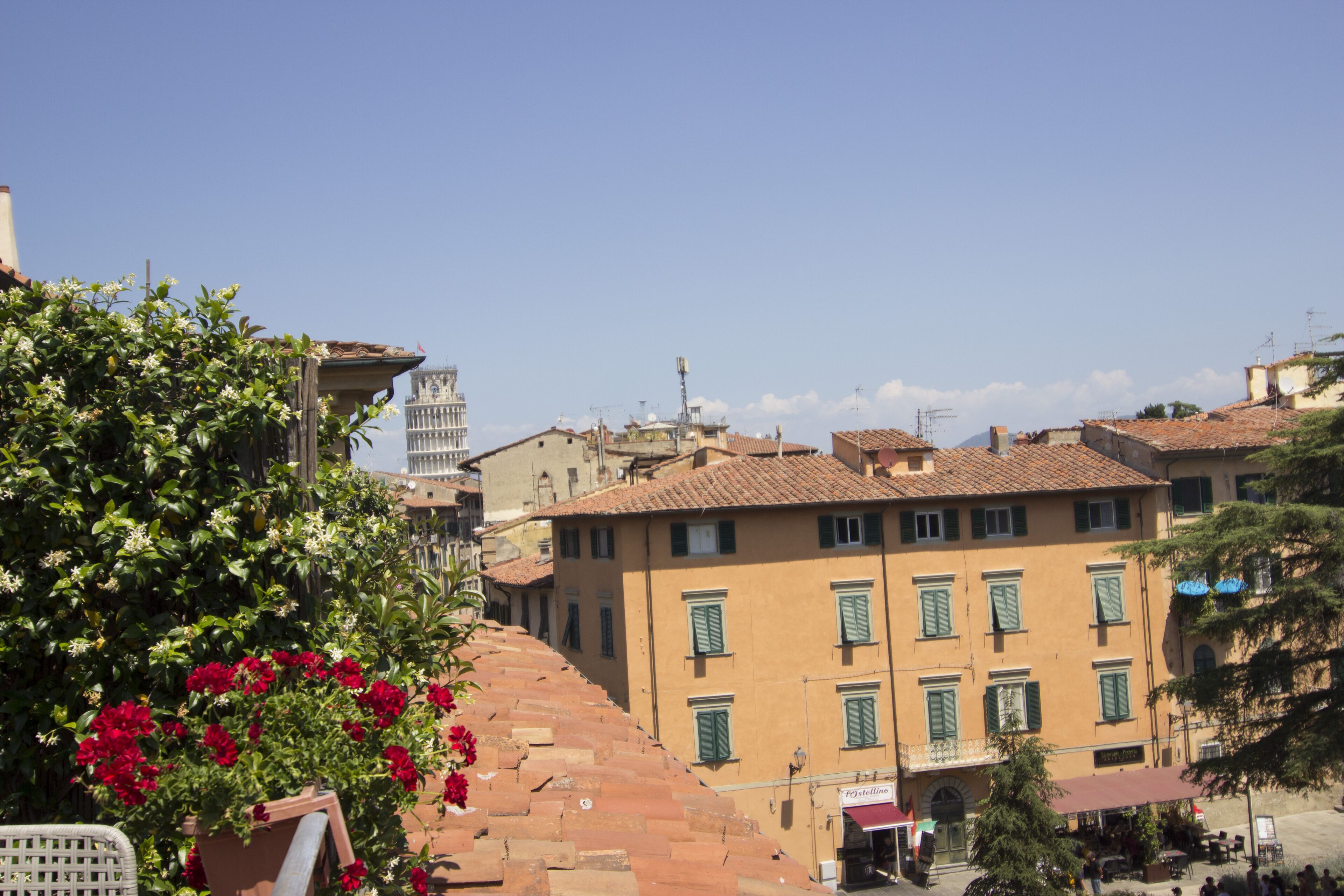 A building with a terracotta roof, a bell tower, and a sign for a restaurant.