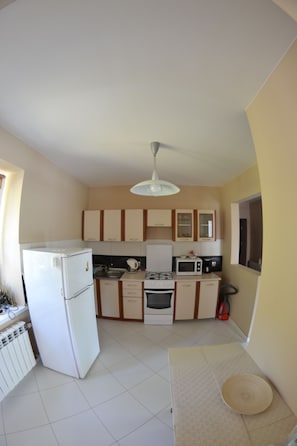 A compact kitchen with white appliances, wooden cabinets, and a tiled floor.