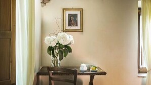 A dining area with a wooden table, chairs, a vase of flowers, and a framed picture on the wall.