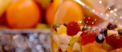 A bowl of fruit salad with a spoon in it, placed on a table with a decorative doily.