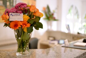 Un ramo de flores con una tarjeta que dice "ALPHA" en un jarrón de vidrio transparente sobre una encimera de granito.