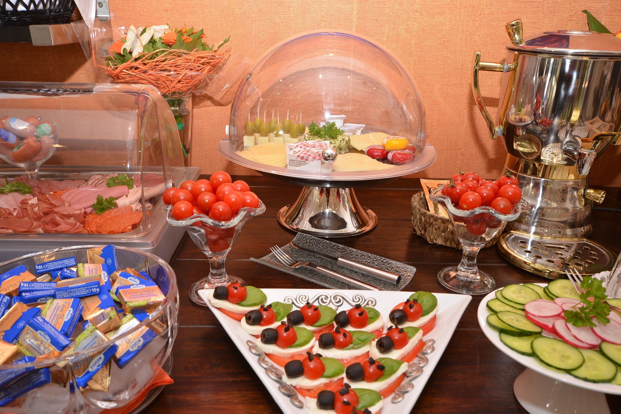 Buffet com diversos alimentos, incluindo queijos, carnes e legumes.