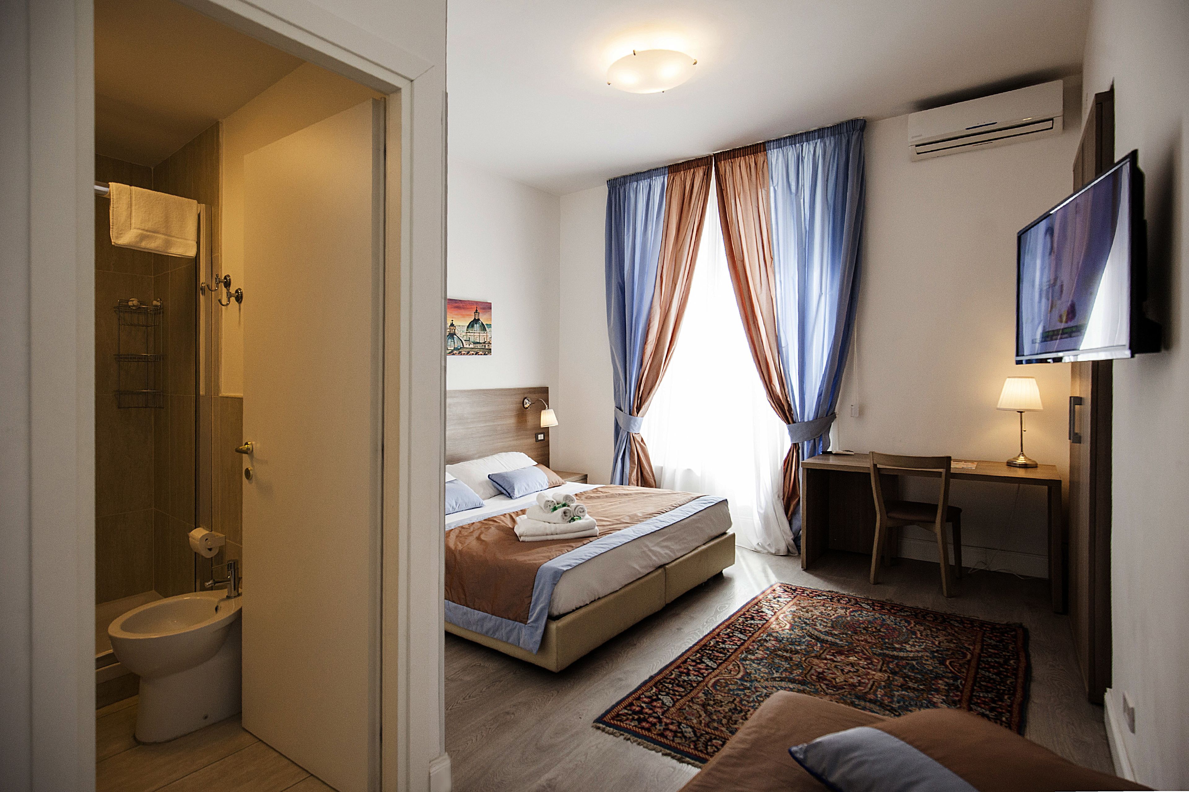 Une chambre d’hôtel équipée d’un lit, d’un bureau, d’une télévision et d’un espace douche.