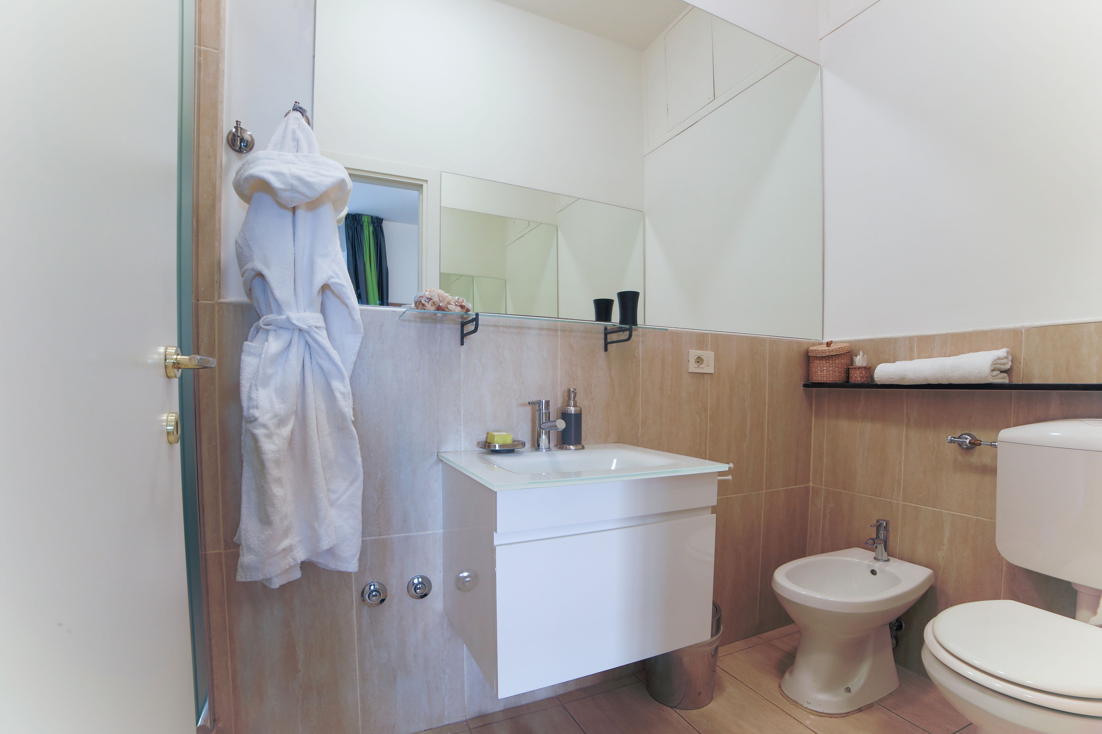 A bathroom with a white sink, a bidet, a toilet, and a mirror.
