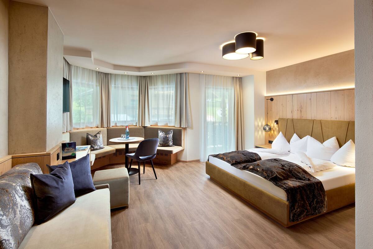 A modern hotel room with a bed, a sofa, a desk, and a chair.