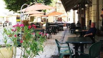 Un café en plein air avec des tables, des chaises, des parasols et des plantes en pot.