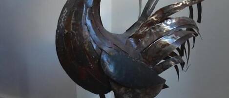 A metal rooster sculpture on a carpeted floor.