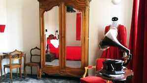 A room with a wooden wardrobe, a red chair, a desk, and a gramophone. - Auberge du Puits (Souillac)
