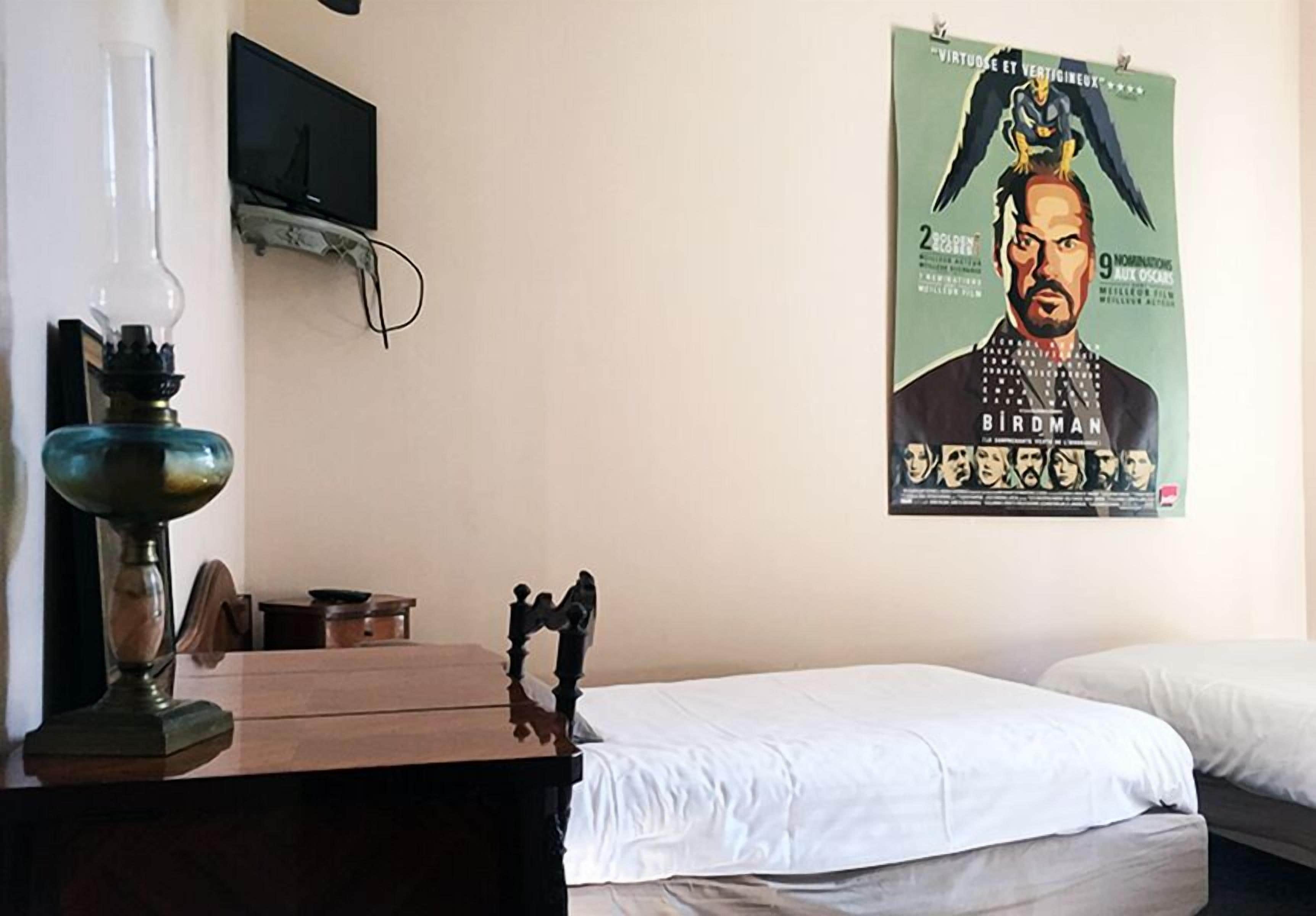 Una habitació d'hotel amb un llit, un escriptori amb una làmpada i un cartell a la paret.