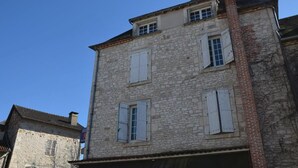 A stone building with multiple windows and shutters. - Auberge du Puits (Souillac)