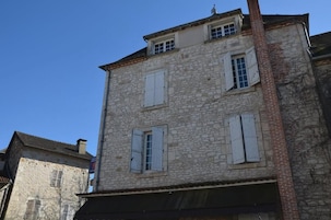 A stone building with multiple windows and shutters.