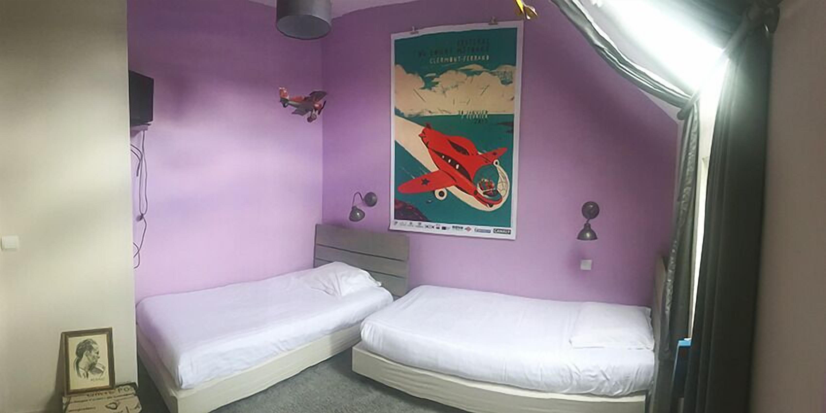 A room with two single beds, a poster on the wall, and a small desk.