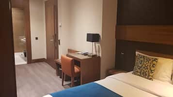 Une chambre d’hôtel comprenant un lit, un bureau, une chaise, une table de chevet et une lampe.