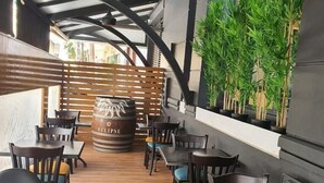 Um espaço de refeições interno com mesas e cadeiras de madeira, divisória de madeira e plantas em vasos.
