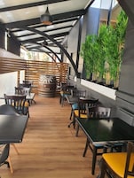 An indoor dining area with wooden tables and chairs, a wooden partition, and potted plants.