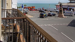 A coastal street with a building featuring balconies and a statue in the foreground. - Afton Hotel (Eastbourne)