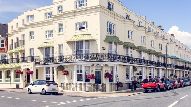A multi-story hotel with a classic facade, a green awning, and a black metal railing. - Afton Hotel (Eastbourne)