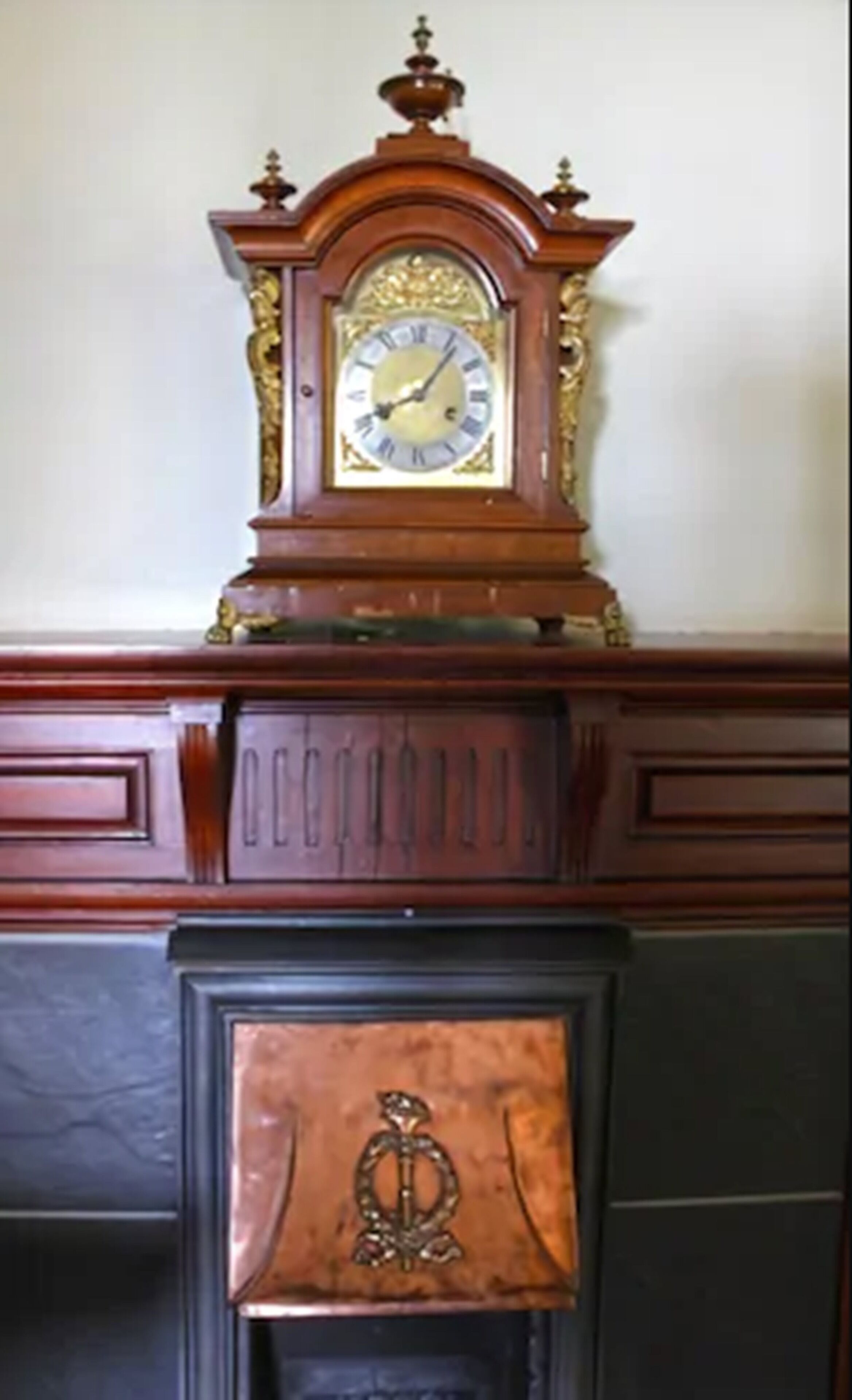 Una repisa de madera con un reloj y un marco decorativo para la chimenea.