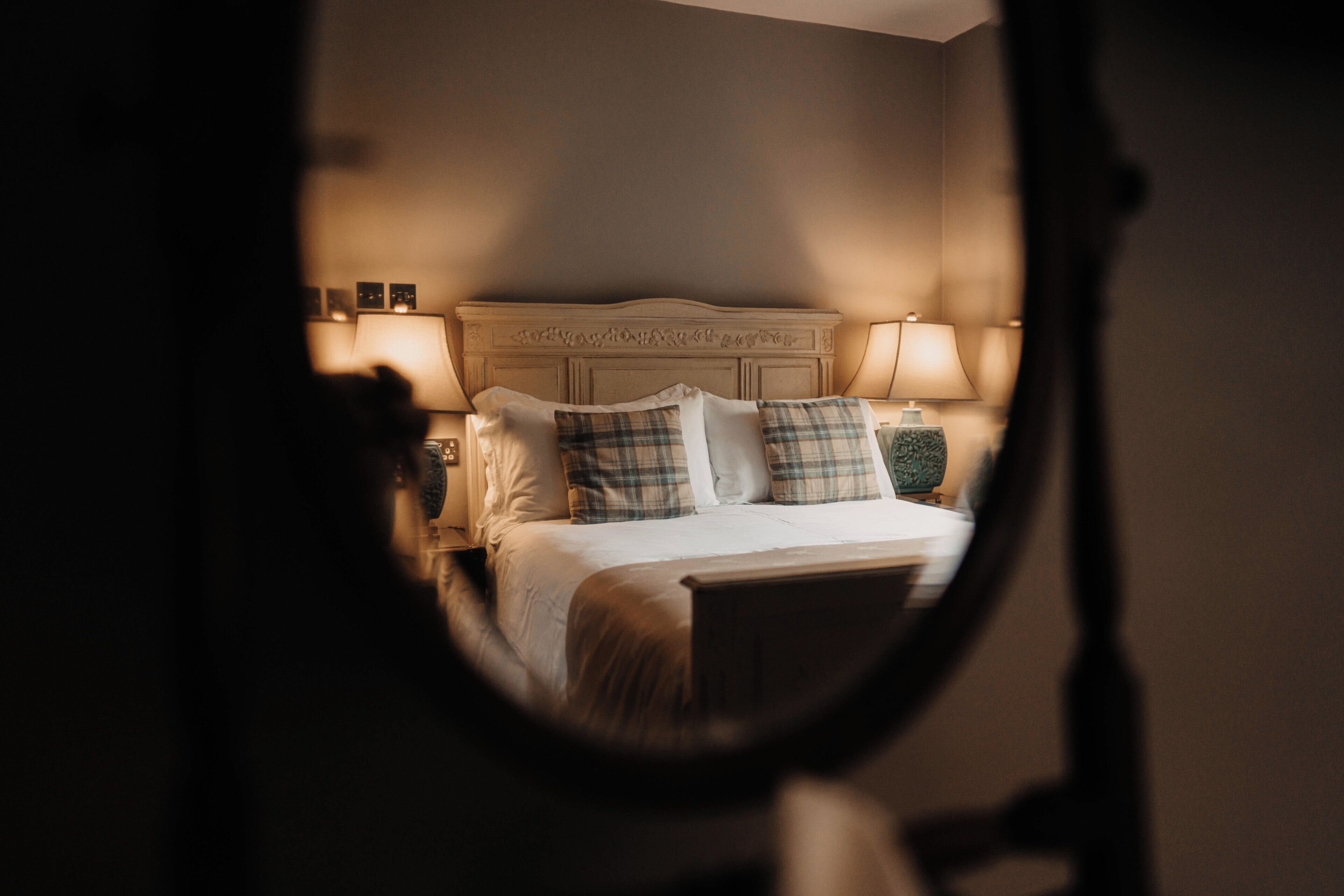 Un dormitorio con cama, almohadas, mesita de noche y lámpara.