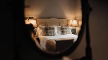 Un dormitorio con cama, almohadas, mesita de noche y lámpara.