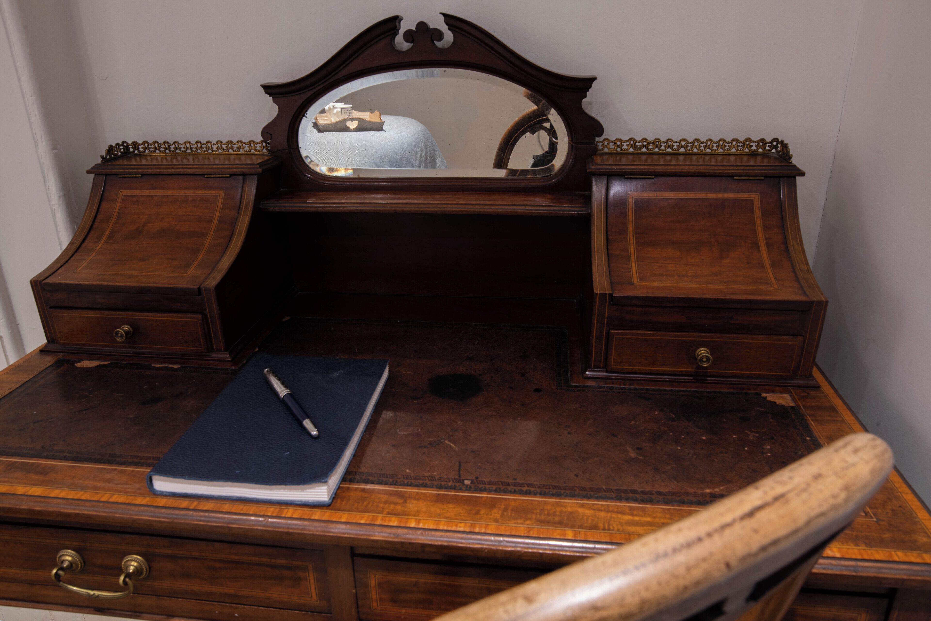 A wooden dresser with a mirror, two drawers, and a notebook on top.