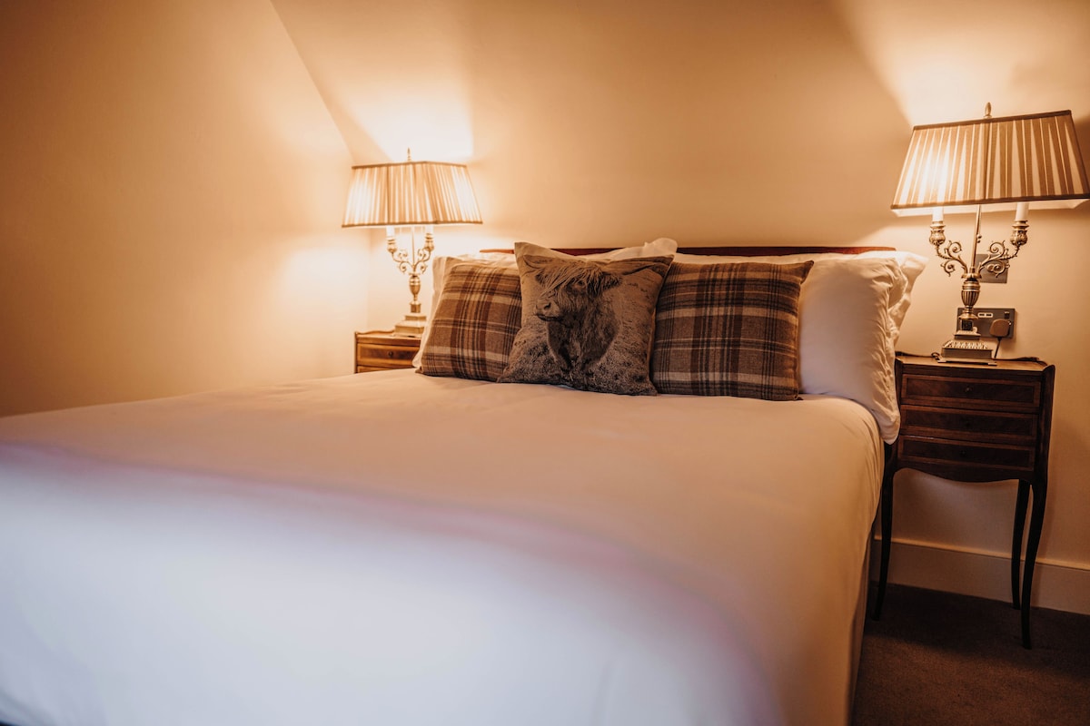 A neatly made bed with a headboard, two bedside tables with lamps, and a wall-mounted lamp.