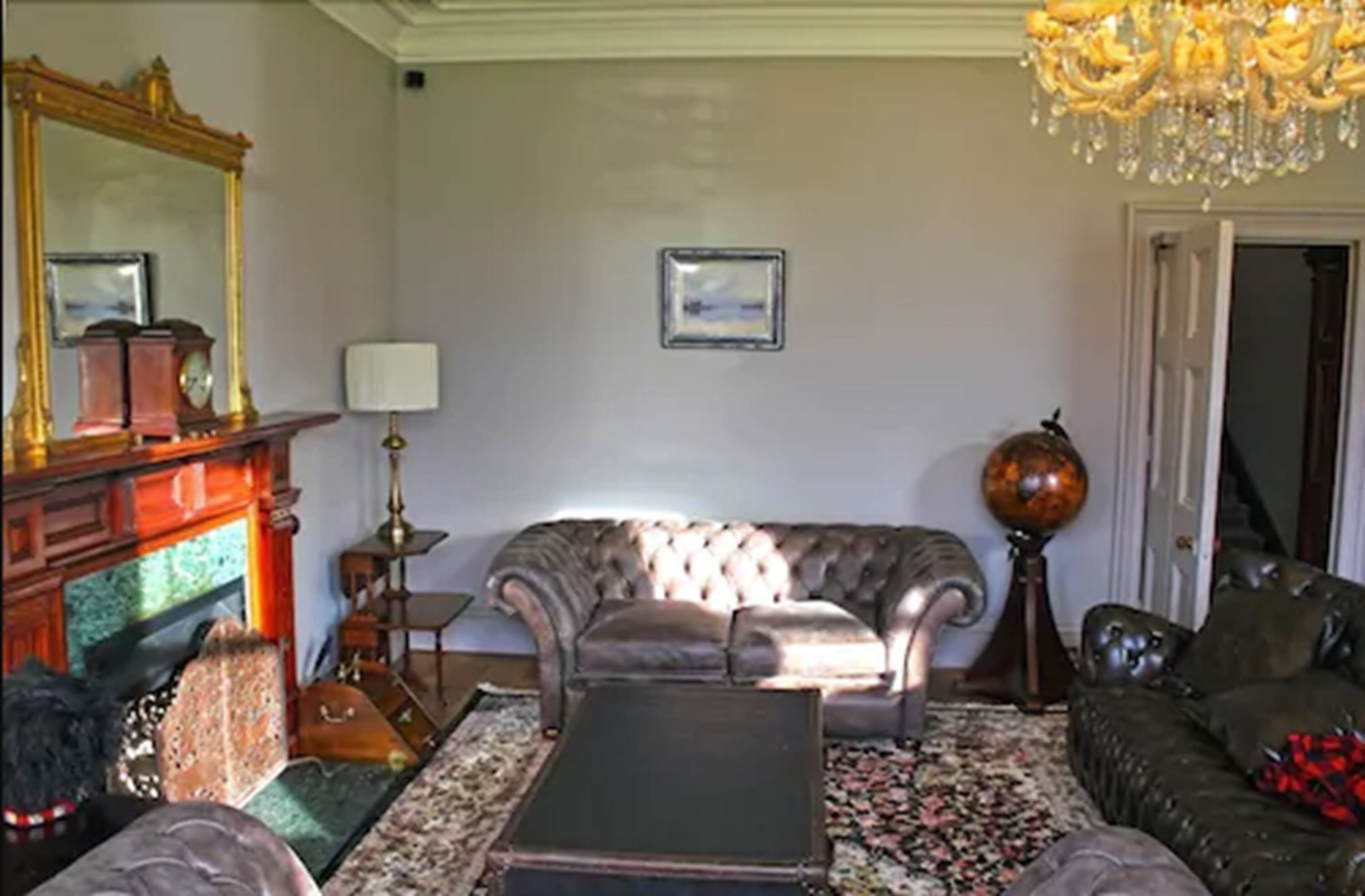 A traditional living room with a fireplace, a sofa, a coffee table, and a chandelier.