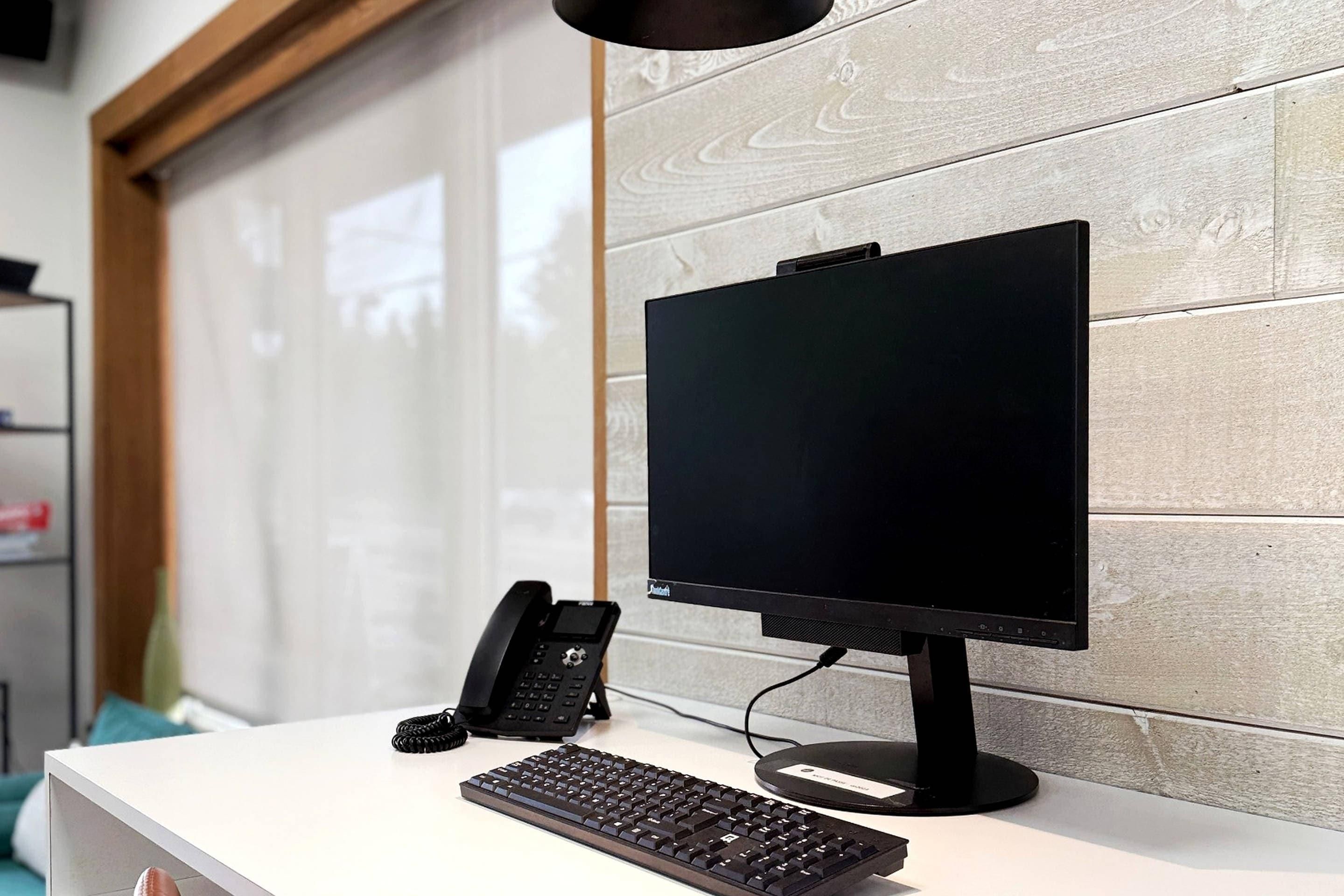 Un mostrador de recepción con monitor de computadora, teclado y teléfono.