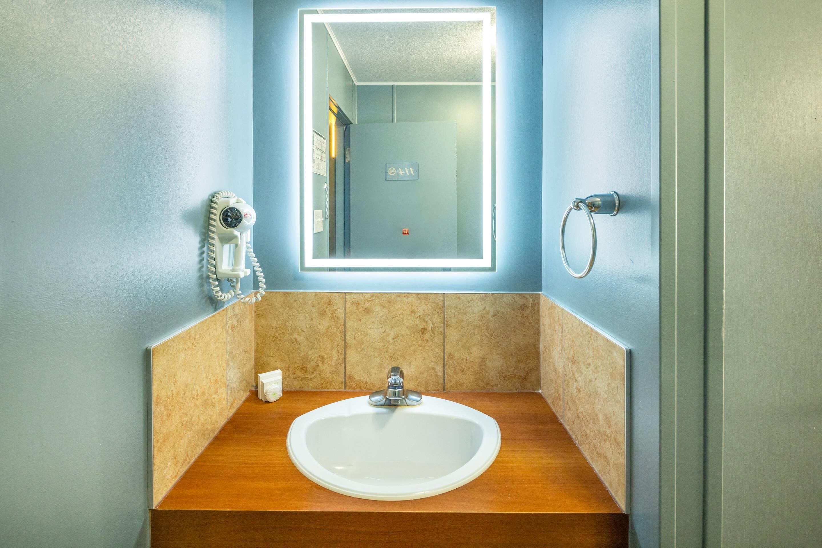 Baño con lavamanos, espejo, toalla y secador de pelo incorporado.