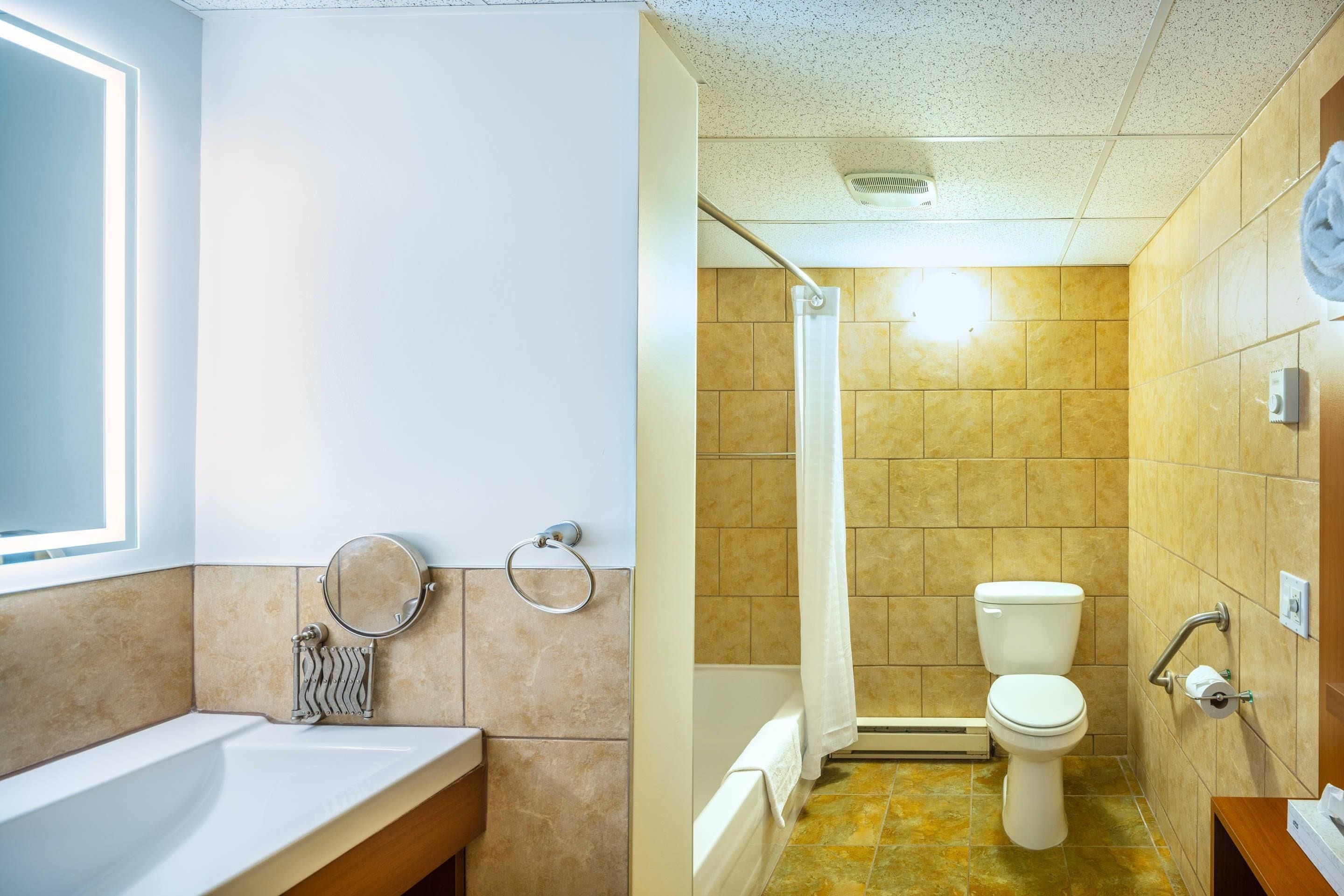 A bathroom with a bathtub, toilet, and a shower curtain.